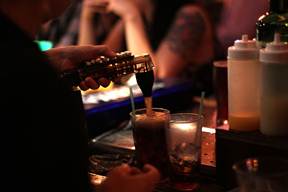 A bartender pours a soft drink into a glass